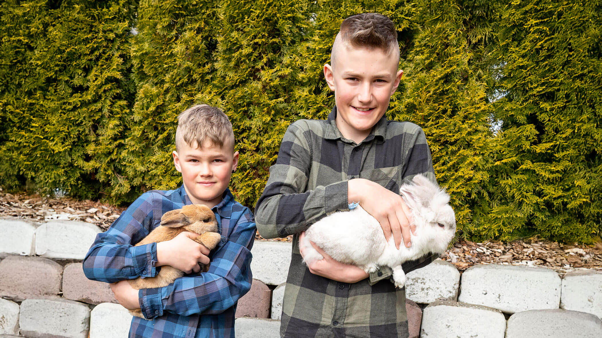 The two host sons Samuel and Matthis each hold a rabbit - Hirschenhof