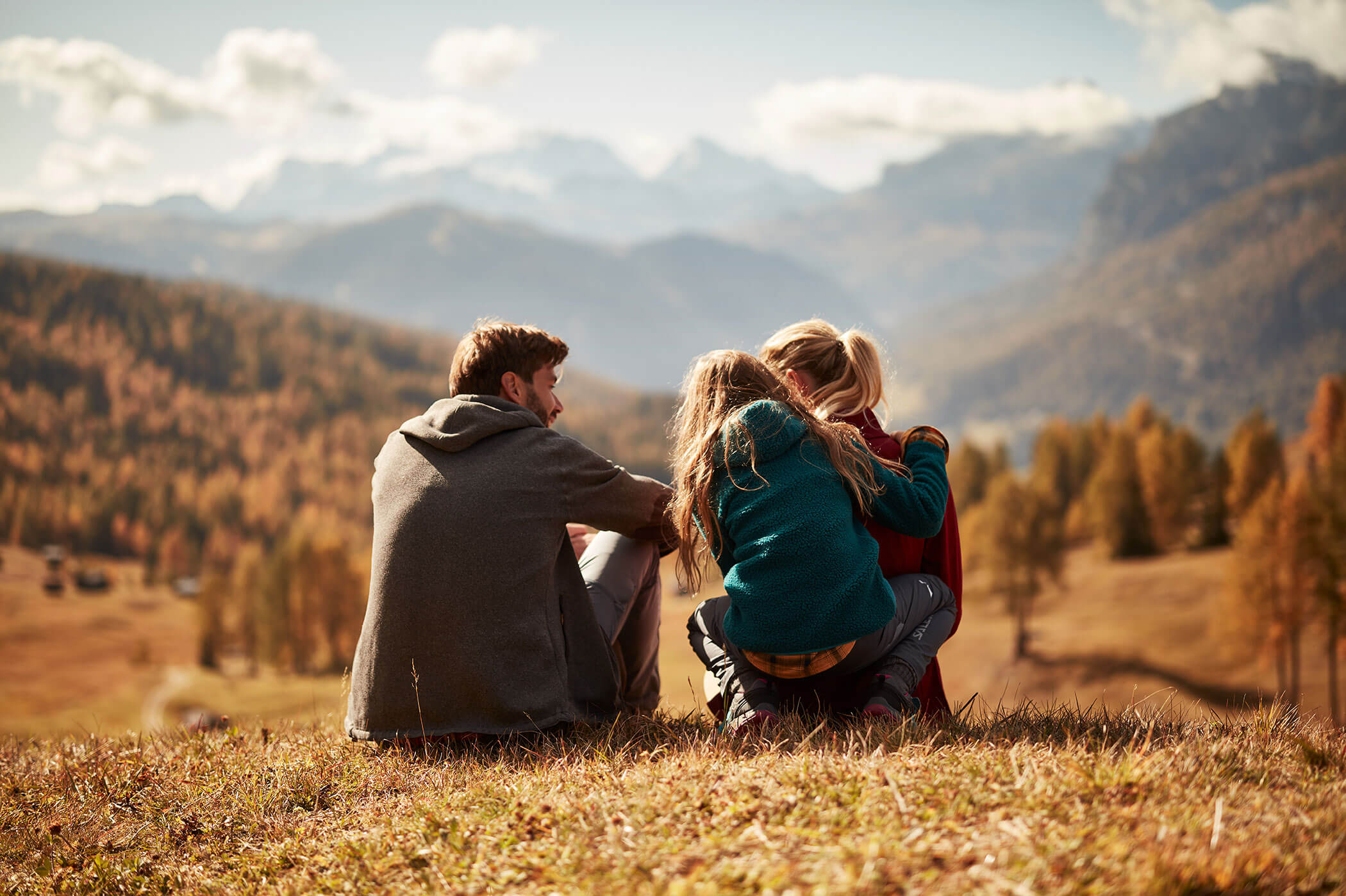 A family sits on a meadow in the mountains - Hirschenhof