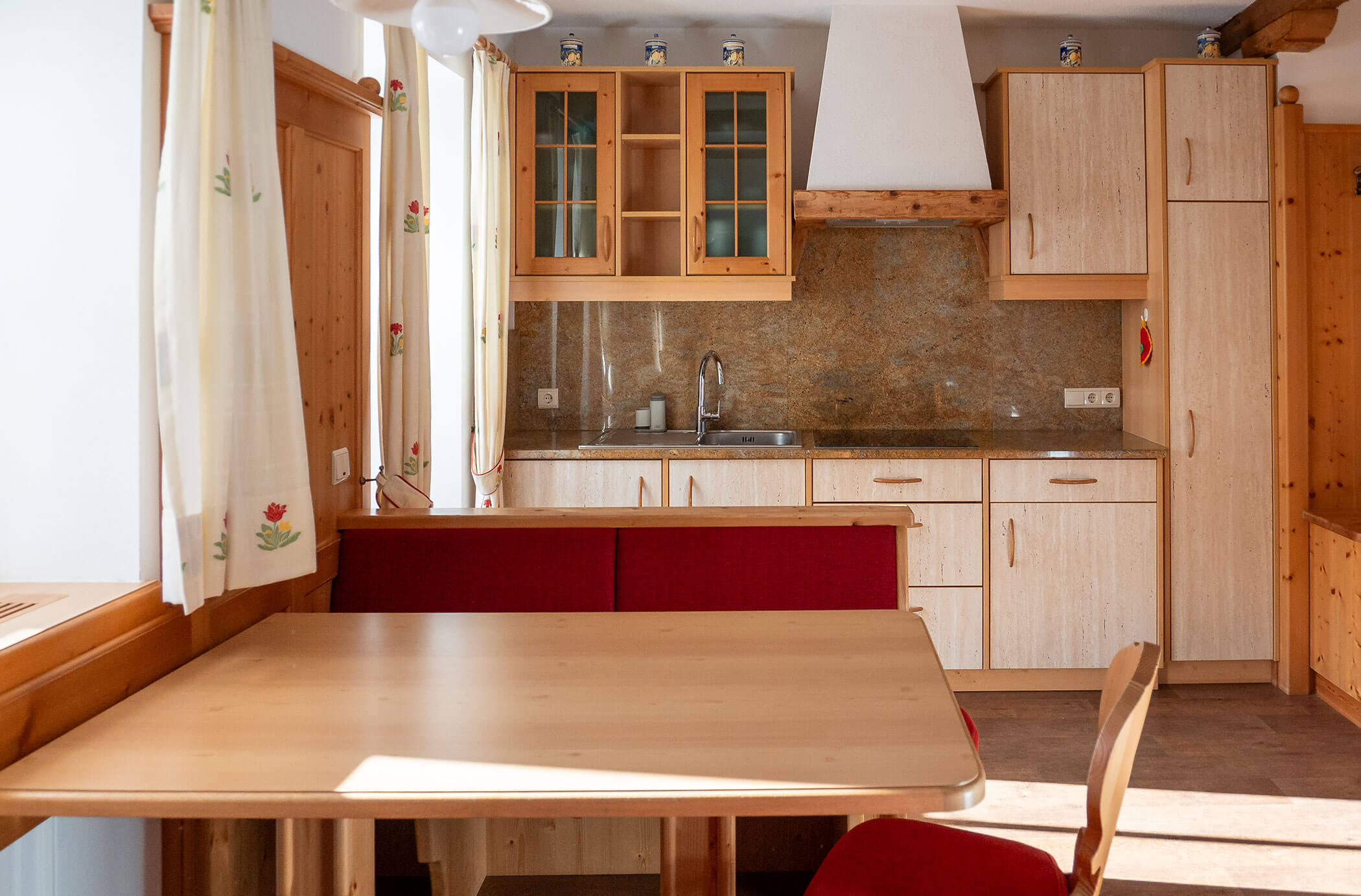 Tavolo da pranzo e angolo cottura dietro di esso nell'appartamento Larice - Hirschenhof