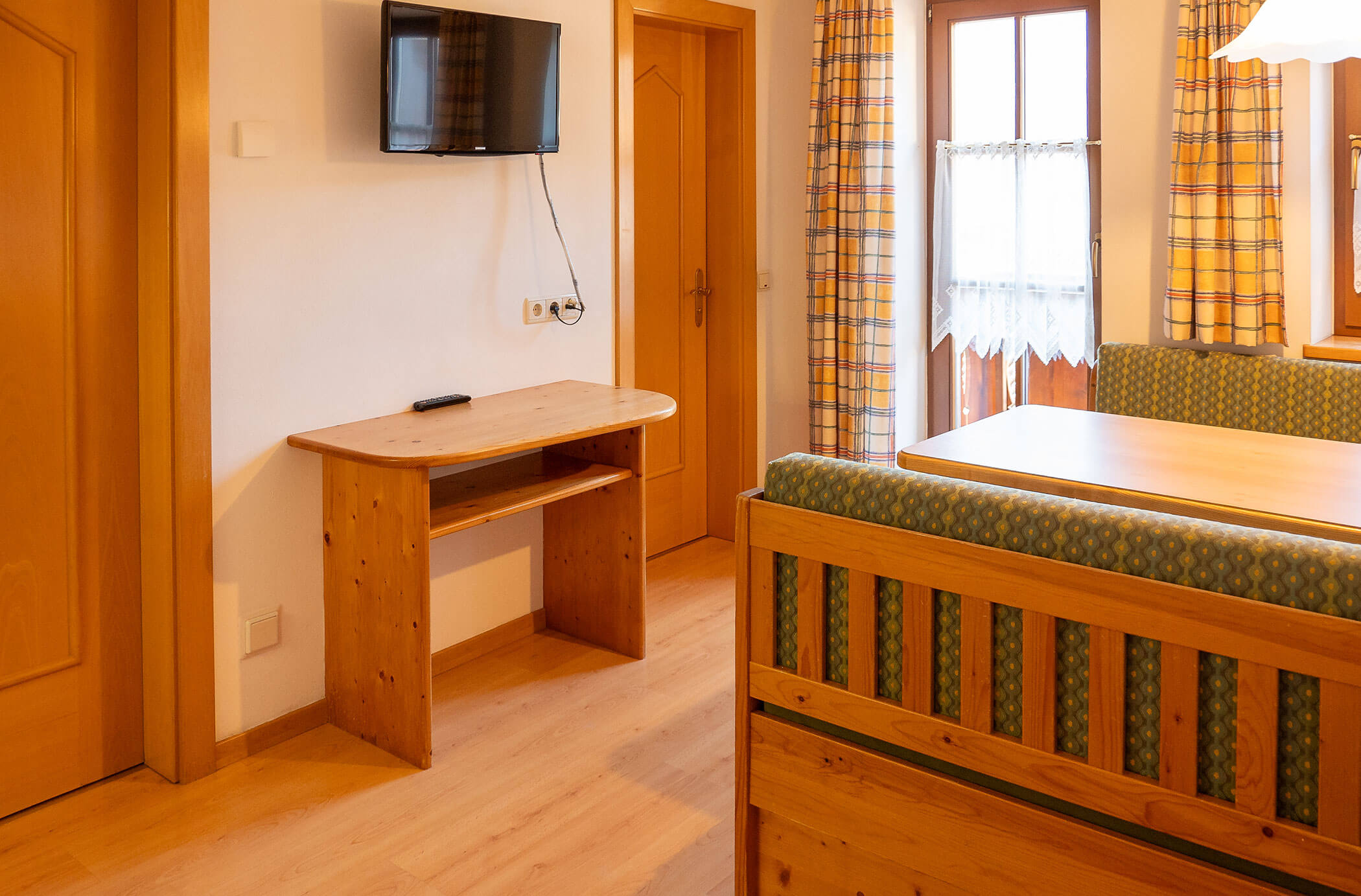 Tavolo da pranzo con panche e TV sulla parete sinistra nell'appartamento Abete - Hirschenhof