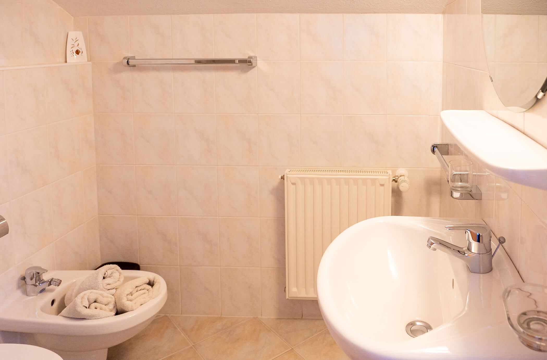 Bagno con lavabo, specchio e bidet con asciugamani nell'appartamento Abete - Hirschenhof