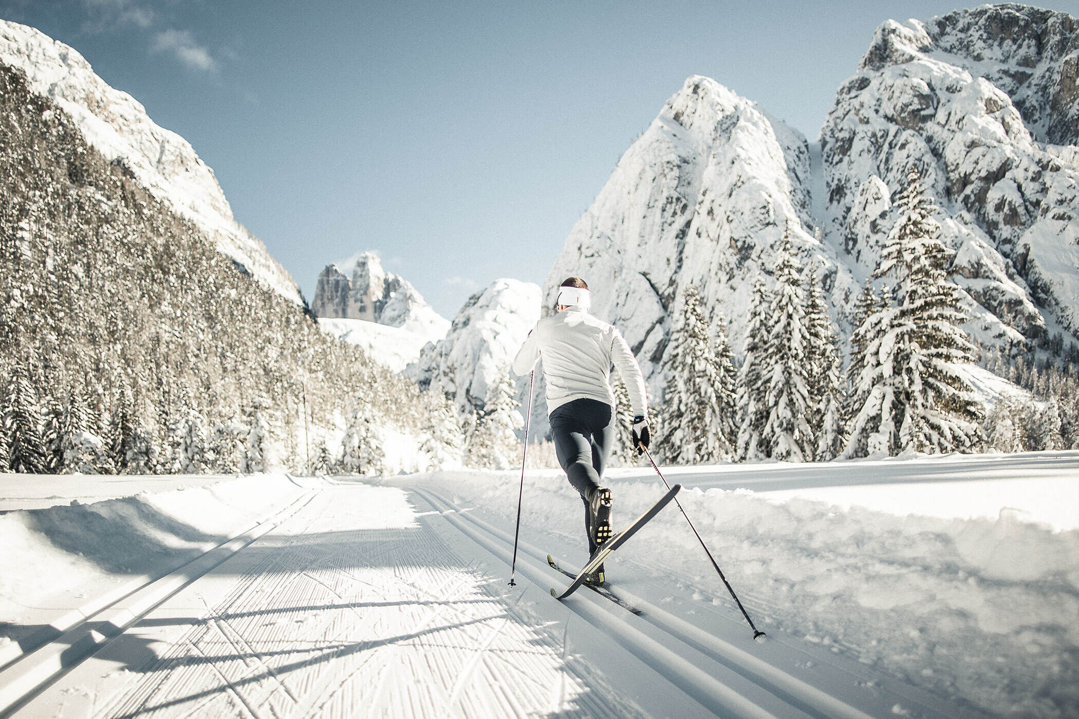 A cross-country skier on the trail between snow-covered mountains - Hirschenhof