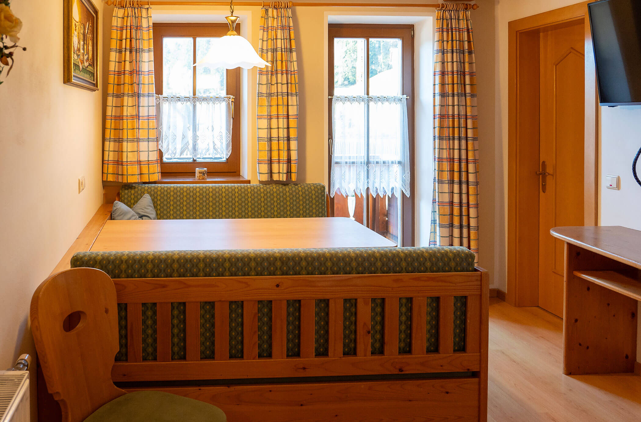 Due panche con tavolo da pranzo e TV accanto nell'appartamento Pino Cembro - Hirschenhof